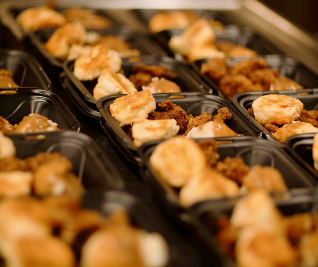 Rows of hot lunches in take-out containers, ready to serve at Outreach on 7th